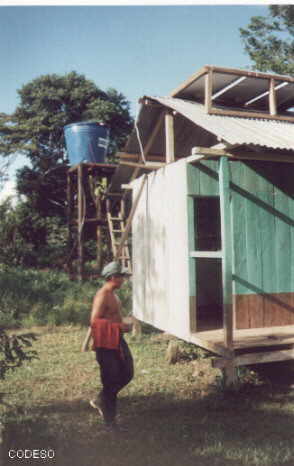 foto Instalación en Yamaram Suku, se puede apreciar los paneles en el techo y el tanque de distribución en el fondo